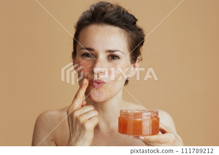 modern woman with face scrub on beige background modern woman with face scrub on beige background 111789212