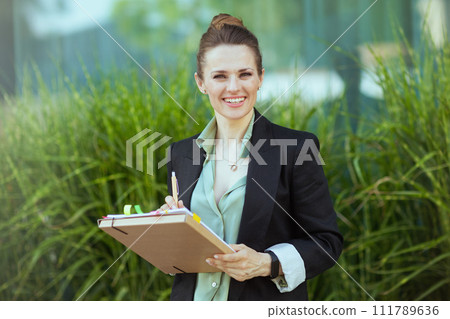 Portrait of smiling modern woman worker in business district 111789636