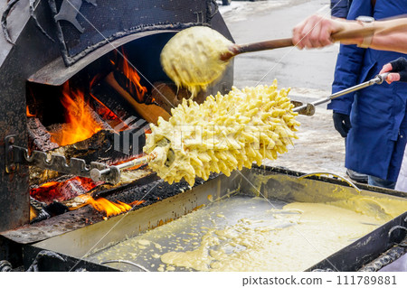 The traditional Lithuanian Polish spit cake is baked on a open fire at fair, Shakotis or spruce pie The traditional Lithuanian Polish spit cake is baked on a open fire at fair, Shakotis or spruce pie 111789881