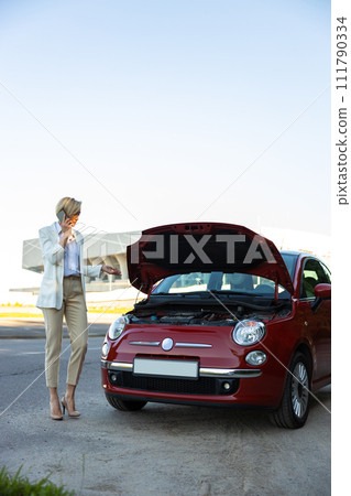 Attractive businesswoman calling to car service for repairing her broken automobile Attractive businesswoman calling to car service for repairing her broken automobile 111790334