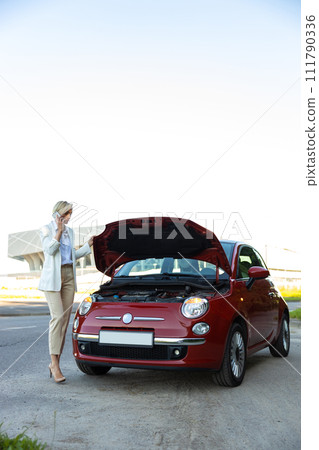 Attractive businesswoman calling to car service for repairing her broken automobile Attractive businesswoman calling to car service for repairing her broken automobile 111790336