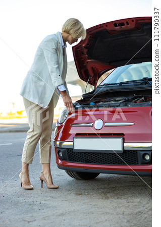 Woman standing near broken down car with popped up hood having trouble with vehicle Woman standing near broken down car with popped up hood having trouble with vehicle 111790337