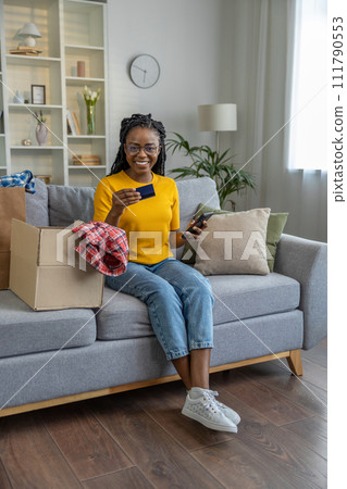 Dark-skinned woman holding credit card in hand and smiling Dark-skinned woman holding credit card in hand and smiling 111790553