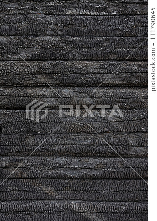 Texture, background, pattern of a charred log wall of a burned-out wooden house. Vertical image. Texture, background, pattern of a charred log wall of a burned-out wooden house. Vertical image. 111790645