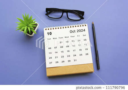 October 2024 desk calendar on blue background. 111790796