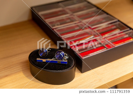 Sets with cufflinks and tie clips on shelf in boutique. 111791359