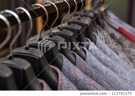A row of men's suits, jackets hanging on a rack for display. 111791375