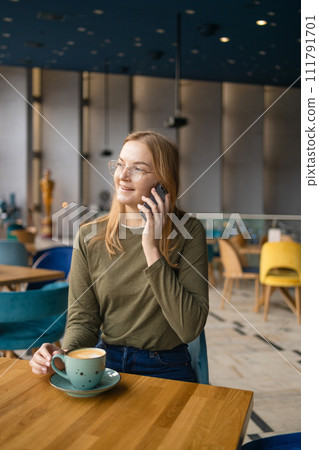 Blonde beautiful stylish caucasian european 30s woman calling with cell telephone while sitting in coffee shop. Blonde beautiful stylish caucasian european 30s woman calling with cell telephone while sitting in coffee shop. 111791701
