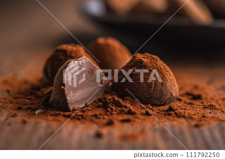 Chocolate truffles covered with cocoa powder on wooden table. 111792250