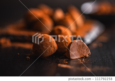 Chocolate truffles covered with cocoa powder on black table. Chocolate truffles covered with cocoa powder on black table. 111792258