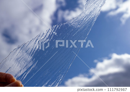 Blue sky and a hand holding thin ice 111792987