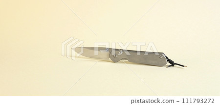 An isolated tourist knife on a beige background. The concept of hunting. An isolated tourist knife on a beige background. The concept of hunting. 111793272