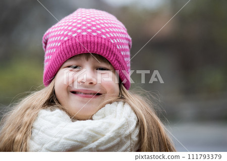 Pretty child girl in warm knitted winter clothes outdoors. 111793379