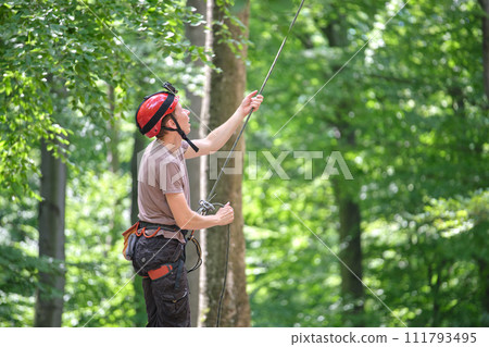 Man belays his partner climber with belaying device and rope. Climber's handsman holding equipment for rock mountaineering security. Man belays his partner climber with belaying device and rope. Climber's handsman holding equipment for rock mountaineering security. 111793495