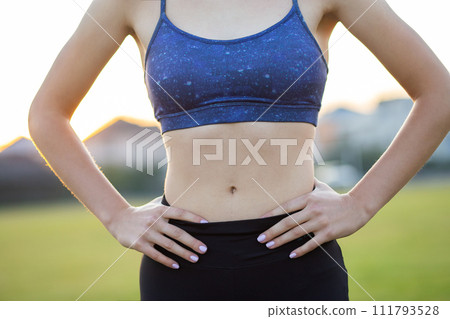 Closeup of a girl slim body in sports clothes. Flat stomach as result of physical training. 111793528