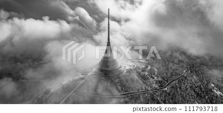 Jested mountain with modern hotel and TV transmitter on the top, Liberec, Czech Republic. Building in clouds. Aerial view from drone.. Black and white image. 111793718