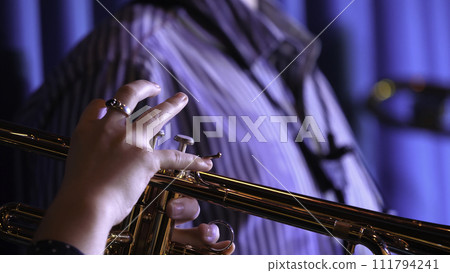 Trumpet player. Trumpeter hands playing brass music instrument close up 111794241