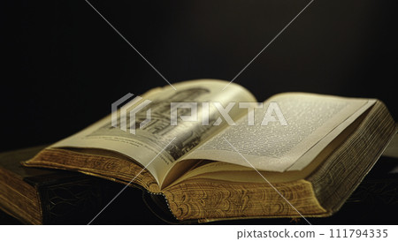 Old book pages detail. Stock footage. Open old book lying on the table with pages turning by wind. Old book pages detail. Stock footage. Open old book lying on the table with pages turning by wind. 111794335