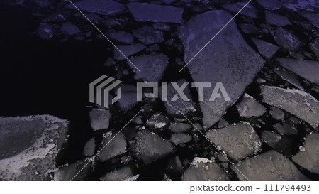 Small cracked pieces of ice on the water surface at the evening. Concept. Close-up view Small cracked pieces of ice on the water surface at the evening. Concept. Close-up view 111794493