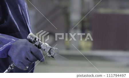 Arm hand holding industrial size spray gun used for industrial painting and coating. Male hand holding paint spray, closeup 111794497