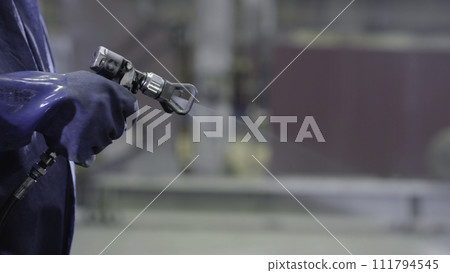 Arm hand holding industrial size spray gun used for industrial painting and coating. Male hand holding paint spray, closeup 111794545