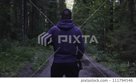 Person in a hood standing. Man in the hood in the woods. Sport in the forest on the nature Person in a hood standing. Man in the hood in the woods. Sport in the forest on the nature 111794546