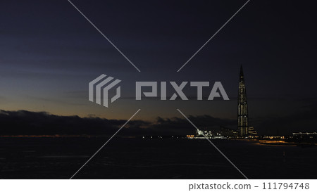 View from the Gulf of Finland on the Gazprom tower illuminated by night lights against the night sky. Concept. Skyscraper Lakhta center Gazprom headquarters night view. View from the Gulf of Finland on the Gazprom tower illuminated by night lights against the night sky. Concept. Skyscraper Lakhta center Gazprom headquarters night view. 111794748