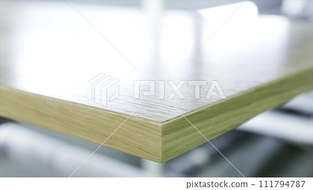 Close-up of large polished wooden board lying on the table at the wooden workshop or factory. Action. Production, manufacture and woodworking industry concept 111794787