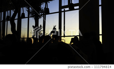Close-up of people silhouettes standing in the dark room near the window at the sunset. Concept. Evening observation platform 111794814