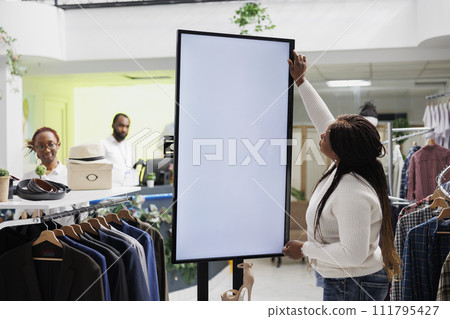 Boutique customer browsing footwear on white blank digital screen in shopping center. African american woman examining shoes brand new collection using interactive whiteboard in store 111795427
