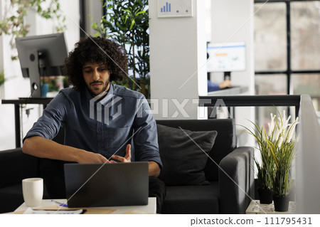 Young arab entrepreneur checking business presentation on laptop in coworking space. Executive manager analyzing company financial report while working in start up office Young arab entrepreneur checking business presentation on laptop in coworking space. Executive manager analyzing company financial report while working in start up office 111795431