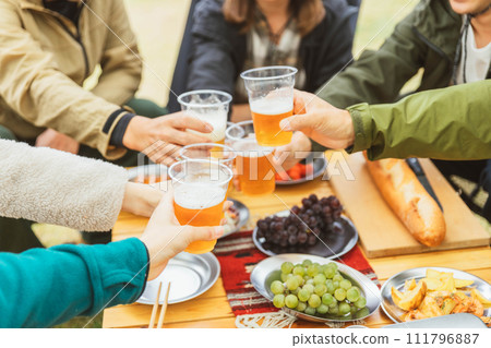 Hands of men and women who drink beer and party with friends at a campsite in autumn and winter Hands of men and women who drink beer and party with friends at a campsite in autumn and winter 111796887
