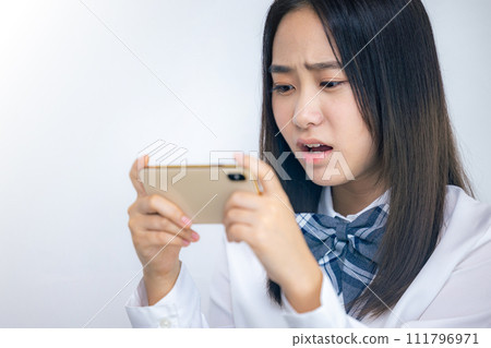 高中女孩看著她的智慧型手機，感到悲傷 111796971