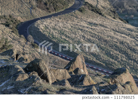 A road going along the slope of mountain range on Arthur's Seat at Edinburgh city on a sunny day. 111798025