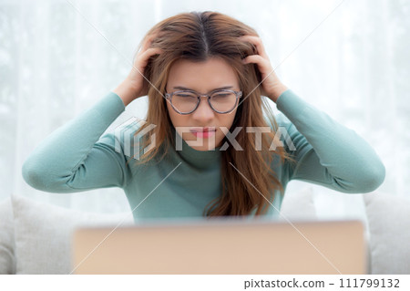 Young asian woman wearing glasses expression with frustration and stress sitting on sofa. 111799132