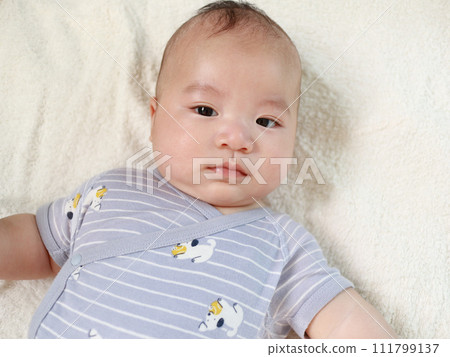 Baby sunbathing looking at camera Baby sunbathing looking at camera 111799137