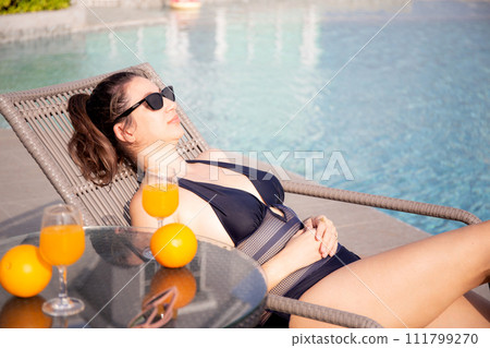 Young caucasian woman sitting on chair beside swimming pool in hotel resort. Young caucasian woman sitting on chair beside swimming pool in hotel resort. 111799270