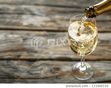 Pouring Champagne into the glass from top view on the wooden table. Pouring Champagne into the glass from top view on the wooden table. 111800130