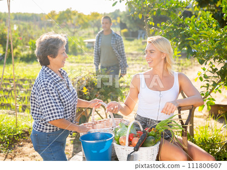 Mom with adults children rejoices at the harvest of vegetables 111800607