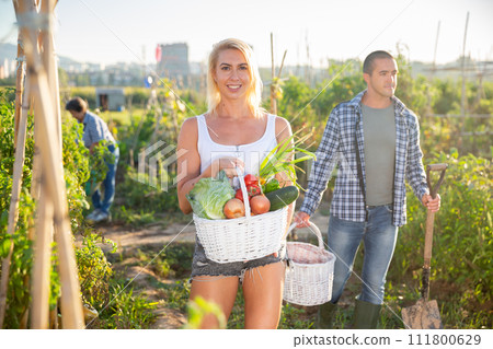 Positive woman posing with harvest of vegetables in garden 111800629