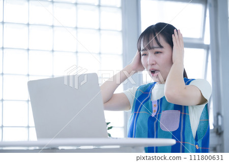 A woman with a tired expression in front of a computer - Image of overtime for childcare workers and caregivers 111800631