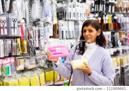 Smiling latina choosing hair rollers in store Smiling latina choosing hair rollers in store 111800681