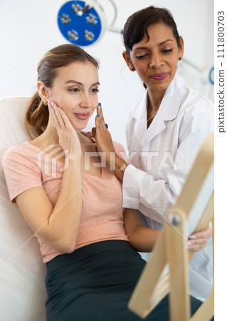 Positive young woman evaluating quality of cosmetological procedures 111800703