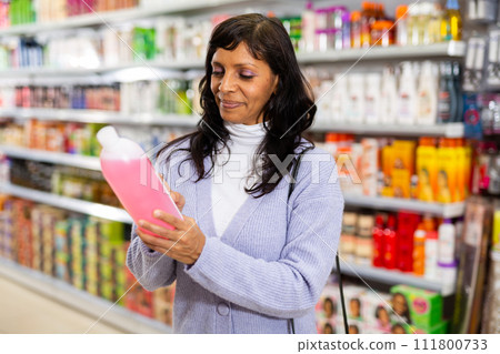 Hispanic woman choosing hair care treatments in cosmetics store Hispanic woman choosing hair care treatments in cosmetics store 111800733