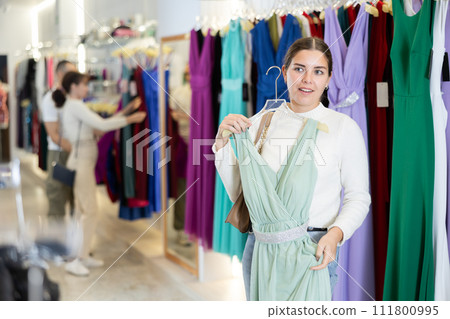 Young girl choosing party dress in clothing store 111800995