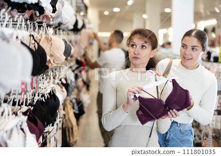 Two women choosing convenient bra in clothing store 111801035