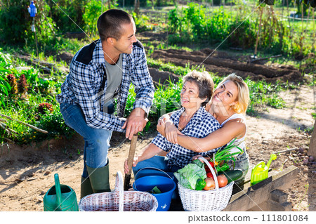 Friendly family discussing good crop of vegetables in garden 111801084