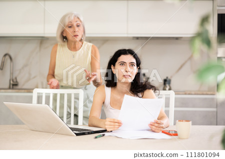 Woman is quarreling with her mother for documents of household at home Woman is quarreling with her mother for documents of household at home 111801094