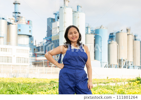 Portrait of girl in construction protective overalls against the backdrop of modern metallurgical or chemical plant 111801264