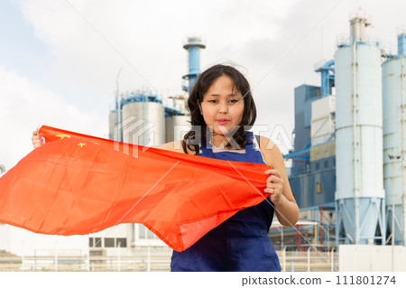 Happy young woman with flag of China against background of factory Happy young woman with flag of China against background of factory 111801274